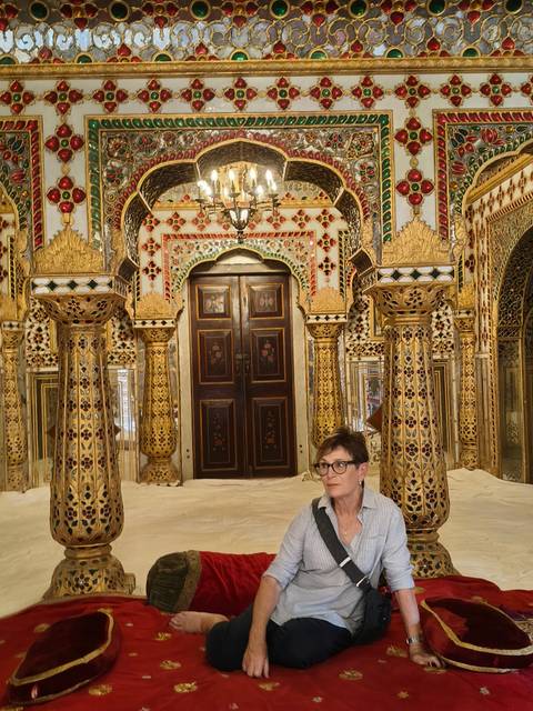 Richly decorated mirrors and gilded columns surround a visitor inside a palace's ornate hall.