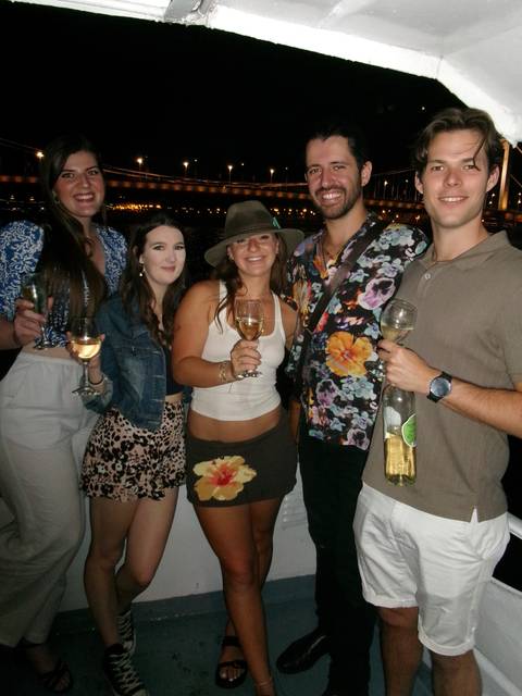 Group of young adults holding wine glasses and smiling during an evening social gathering.