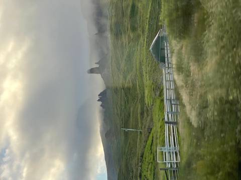 Misty outline of the Old Man of Storr rock pinnacles rising above green slopes under low clouds.