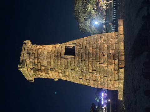 Stone Cheomseongdae Observatory lit up against a dark night sky.