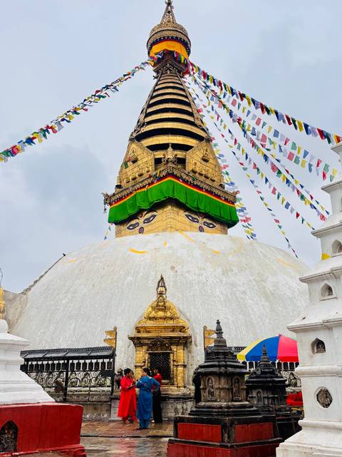 Eyes of Buddha painted on the gilded Swayambhunath stupa tower with colourful prayer flags.