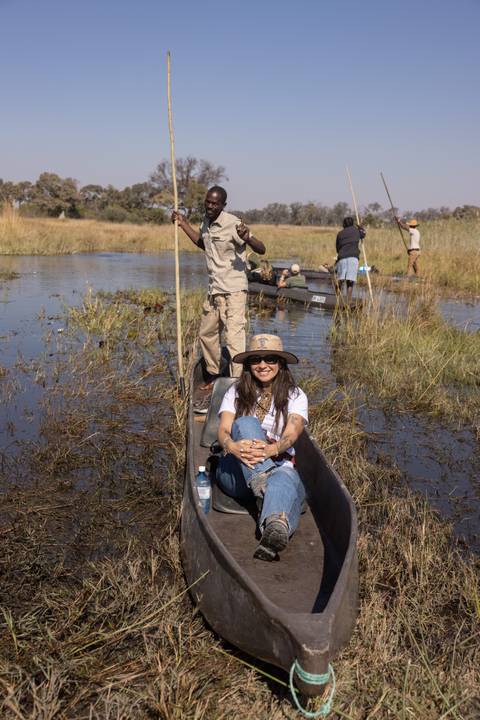 Traveller seated in a traditional mokoro canoe gliding through the marshy channels of the Okavango Delta.