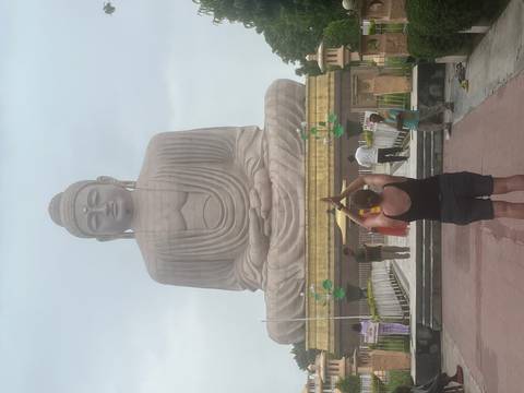 A traveler performs a yoga salute facing the towering Buddha statue at Bodhgaya.