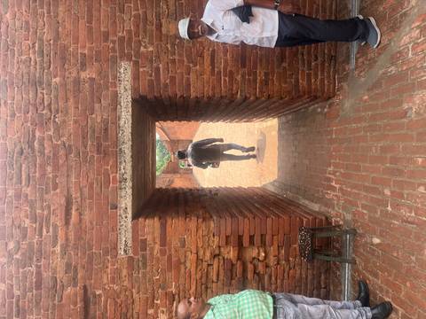 Man walks through a sunlit brick corridor with rough textured walls.