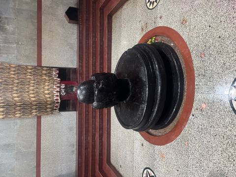 Polished black stone Shiva lingam set on a circular base inside a temple sanctuary.