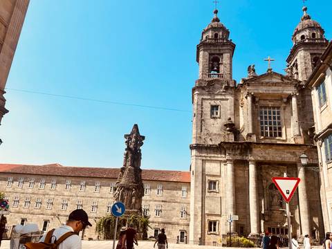 Historic stone church façade and ornate monument under clear blue sky in Santiago de Compostela.