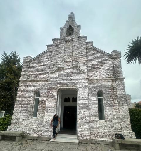 Chapel entirely covered with white seashells creating a textured façade under grey sky.