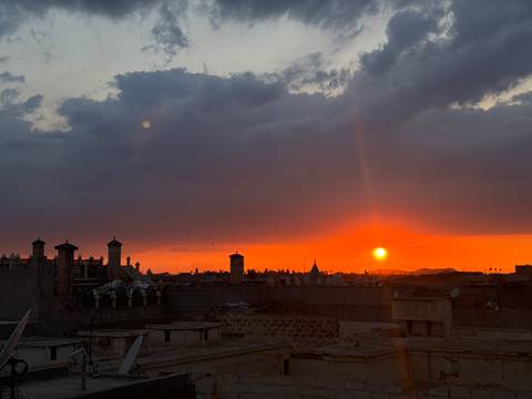 Fiery sunset over the rooftops of Fes medina with silhouetted minarets.