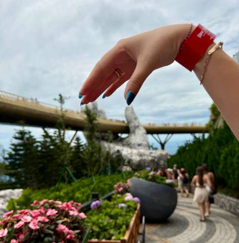 Tourist hand playfully frames the famous Golden Bridge supported by giant stone hands.