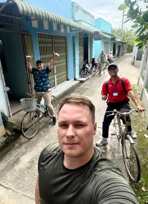 Cycling tour selfie in a narrow alley, with guide and traveller on bicycles.