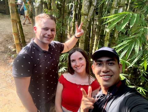 Selfie of three friends flashing peace signs in a bamboo grove.