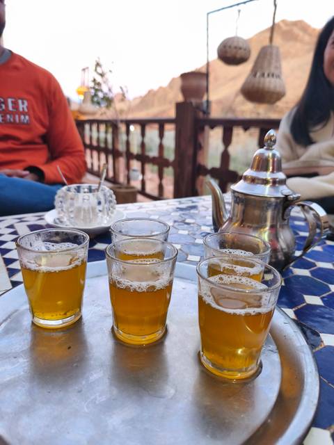 Traditional Moroccan mint tea glasses and silver teapot on a patterned mosaic table.