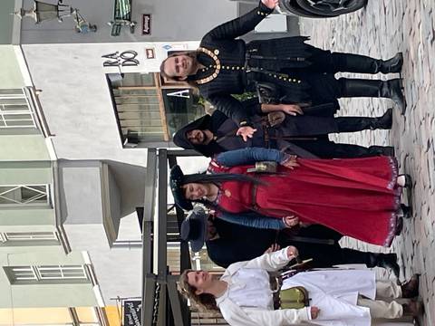 Street performance group dressed in medieval costumes posing in an old town square