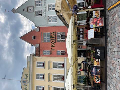Colorful medieval façades of an old town restaurant square with outdoor menus and umbrellas