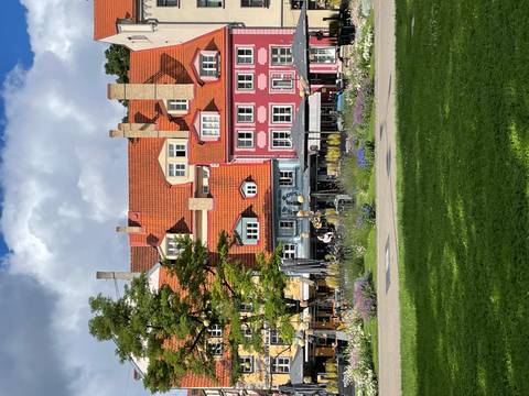 Colorful historic houses with red roofs fronting a green city park on a sunny day