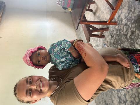 Young woman smiles while holding a baby indoors at a local community center