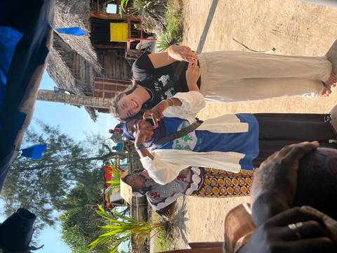 Friendly interaction between travellers and a local woman near a tropical seafront village