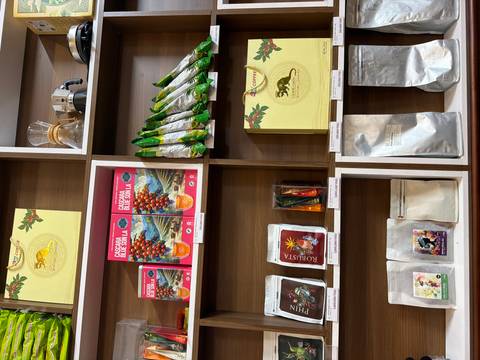 Wood-shelved shop display with various Vietnamese coffee beans, teas and brewing equipment.