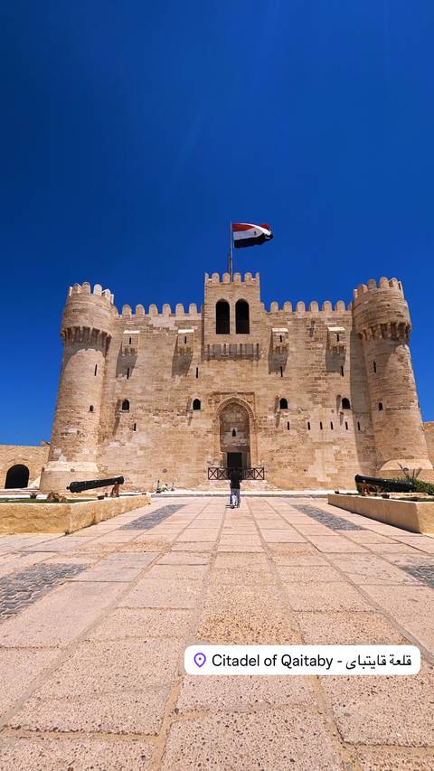 Front façade of a medieval-looking fortress with a visitor standing at entrance