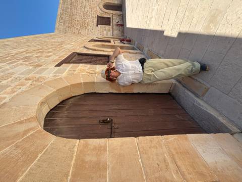 Woman leaning against an arched wooden door of a historic stone building