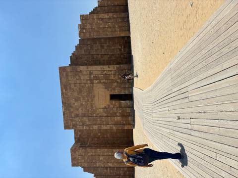 Entrance of an ancient stone structure at Saqqara with wooden walkway leading in