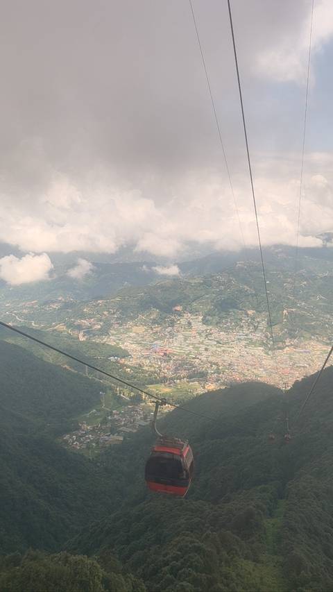 Hazy aerial view of a sprawling Nepalese valley village taken from a cable car high above the hills.