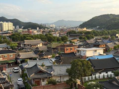 Rooftop view across Jeonju Hanok Village’s traditional tiled houses with distant city and mountain backdrop.