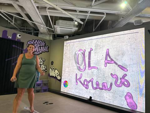 Instructor stands beside a large digital graffiti display during an indoor workshop.