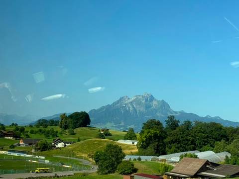 Distant mountain peak viewed through a tour bus window with reflections and glare.