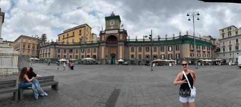 Panoramic view of Piazza Dante in Naples with historic green-fronted architecture and casual visitors.