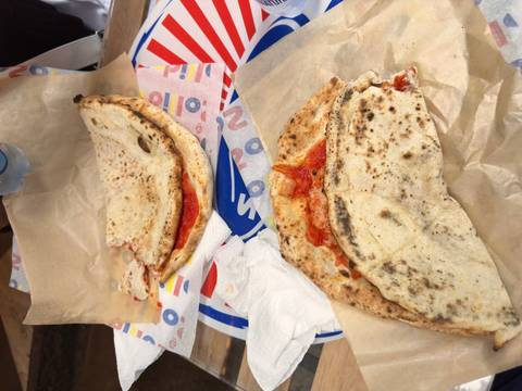 Two folded street pizzas on paper wrap showcase classic Neapolitan fast food.