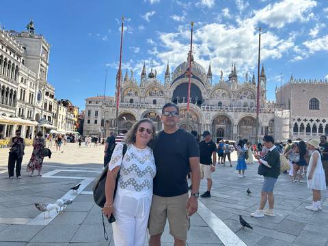 Couple standing in Piazza San Marco with St Mark’s Basilica and lively crowds in the background.
