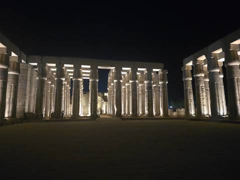 Illuminated colonnade of Luxor Temple glowing against the night sky.