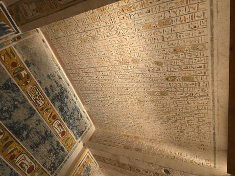 Detailed hieroglyphic inscriptions and painted ceiling inside an ancient Egyptian tomb chamber.