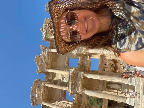 Smiling traveler taking a selfie in front of the ancient Library of Celsus ruins under clear blue sky
