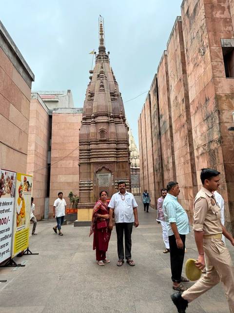 Temple courtyard with sandstone shikharas where worshippers and police officers stand during a busy day.