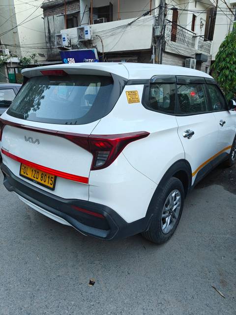 Rear side view of a white Kia SUV with a yellow Delhi license plate and a tour sticker on the window.