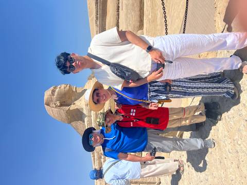 Smiling family posing in front of the Great Sphinx under a bright blue Egyptian sky