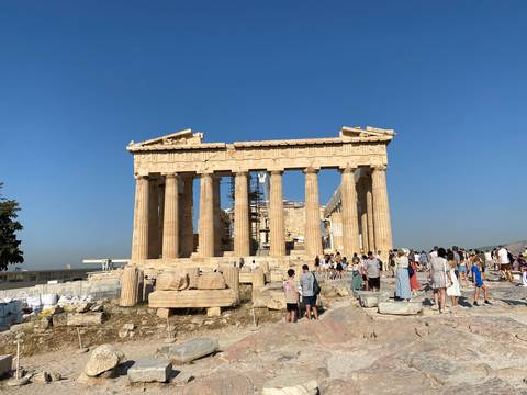 Visitors explore the ancient Parthenon atop the Acropolis under a clear blue sky