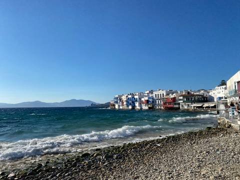 Coastal scene of whitewashed waterside houses facing a choppy turquoise sea on a windy day