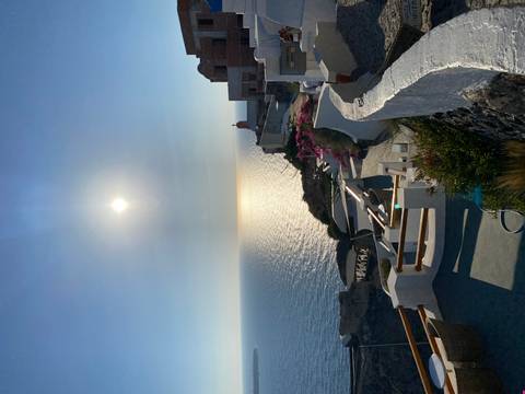 High sun over the caldera cliffs of Santorini with sparkling sea below