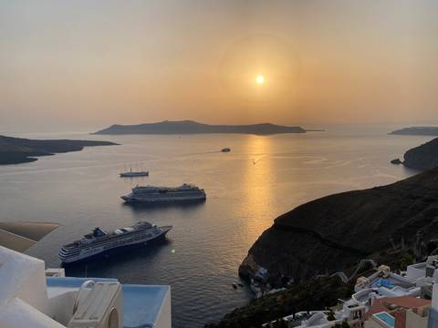 Cruise ships anchored in Santorini’s caldera with golden sun reflection on the water