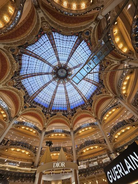 Elaborate glass and iron dome ceiling of a grand department store with ornate balconies