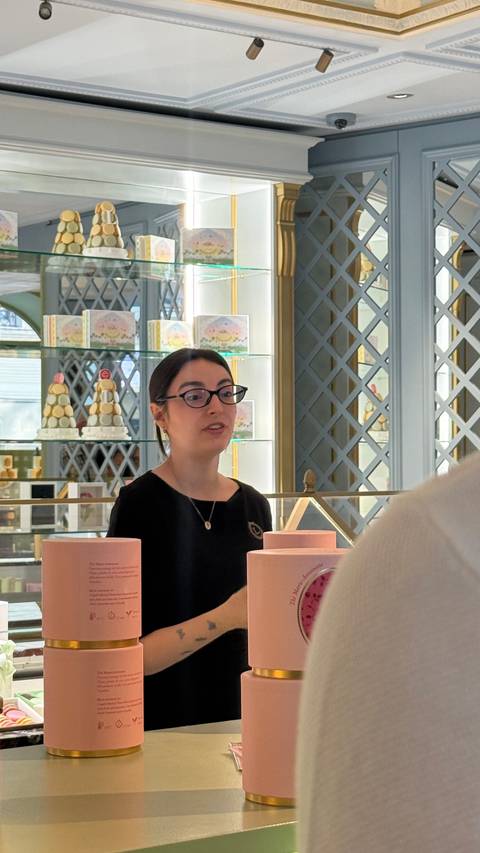 Pastry shop staff explaining confections inside an elegant boutique interior