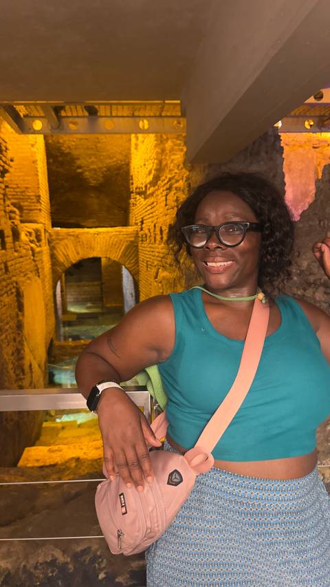 Smiling visitor poses inside a dimly lit ancient brick corridor with arched passageways.