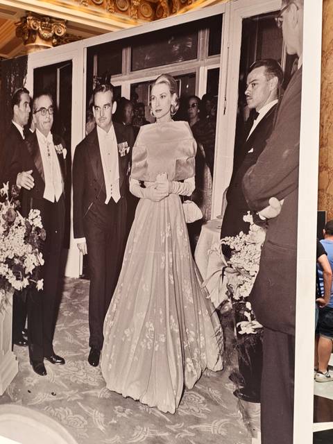Exhibit photo of dignitaries in evening dress displayed in a museum with a visitor partly visible.