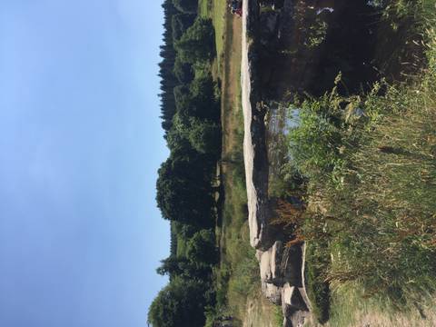 Rural stone clapper bridge crossing a small stream in a green countryside setting under clear skies