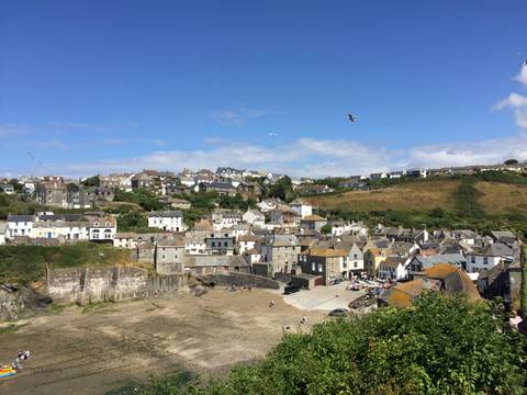 Panoramic view of Port Isaac’s clustered white and stone houses around its harbour on a sunny day