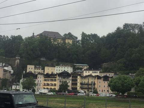 Cluster of multi-coloured hillside houses below a wooded cliff on a misty day