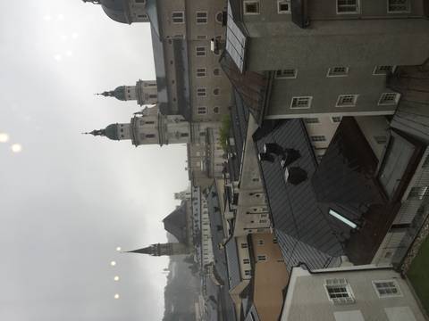Rainy cityscape of Salzburg rooftops with cathedral domes and church spires seen from above